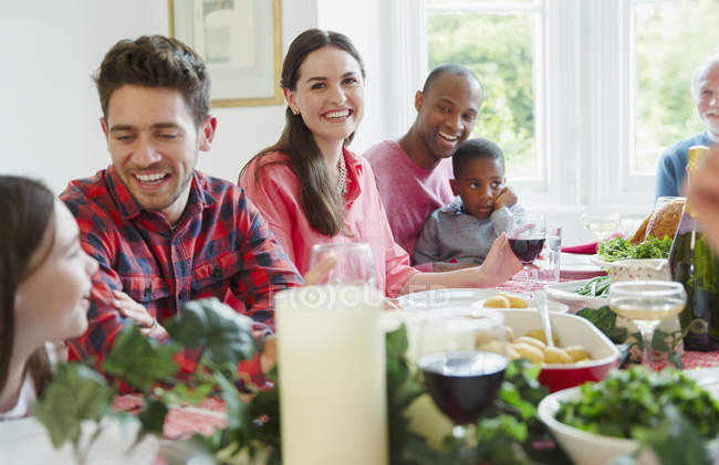Retrato mujer sonriente disfrutando de la cena de Navidad con la familia en la mesa - foto de stock