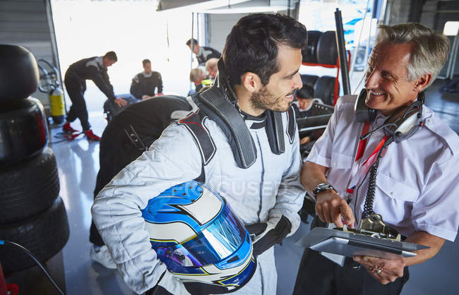 Manager e pilota di Formula 1 auto da corsa parlando in garage di riparazione — Foto stock
