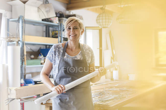 Portrait smiling stained glass artist holding drawings in studio — Stock Photo