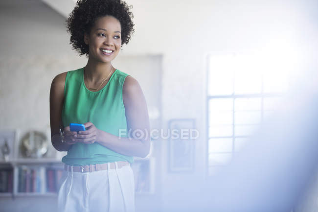 Ritratto di donna con capelli ricci neri che tiene il telefono cellulare — Foto stock