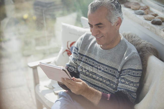 Hombre mayor usando tableta digital en el porche del sol - foto de stock