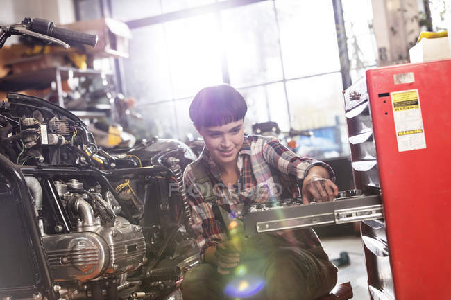 Motorradmechanikerin holt Werkzeug aus Werkzeugkiste in Werkstatt — Stockfoto