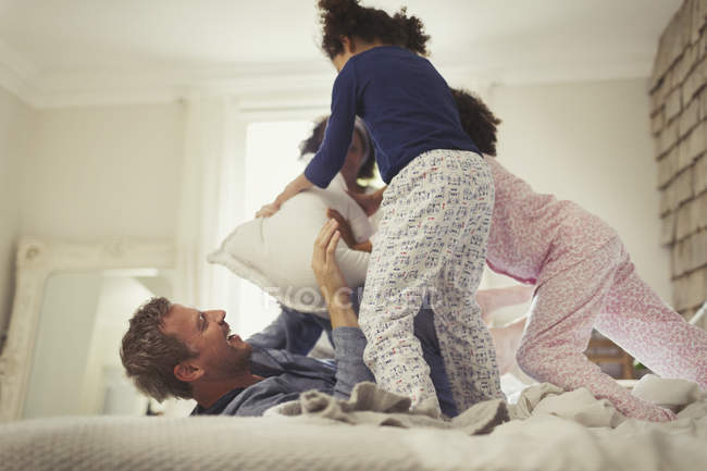 Verspielter Multi-Ethos-Kopfkissen-Kampf zwischen Vater und Tochter auf dem Bett — Stockfoto