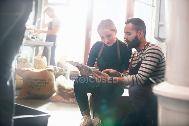 Coffee roasters meeting, looking at clipboard and cell phone — Stock Photo