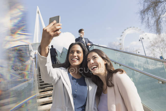 Enthousiaste, souriant femmes amis prendre selfie avec téléphone caméra sur ensoleillé, escaliers urbains, Londres, Royaume-Uni — Photo de stock