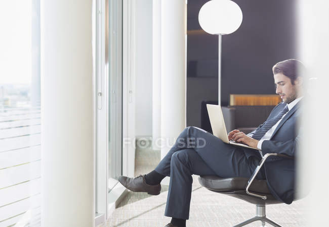 Vista lateral del hombre de negocios utilizando el ordenador portátil en el salón de oficina - foto de stock