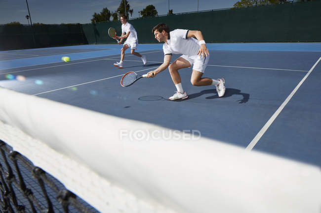 Jeunes joueurs de tennis doubles masculins jouant au tennis sur un court de tennis — Photo de stock