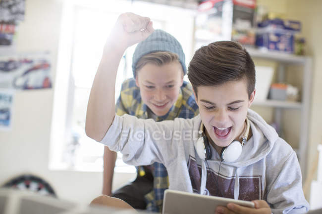 Двоє хлопчиків-підлітків розважаються під час використання цифрового планшета — стокове фото