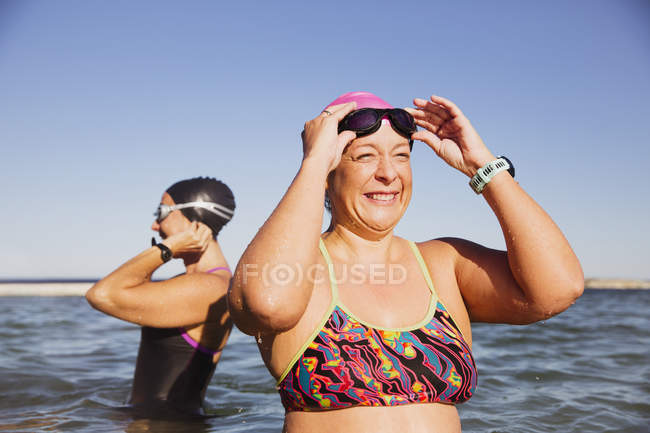 Женщины-пловцы, стоящие у океанской воды на открытом воздухе — стоковое фото