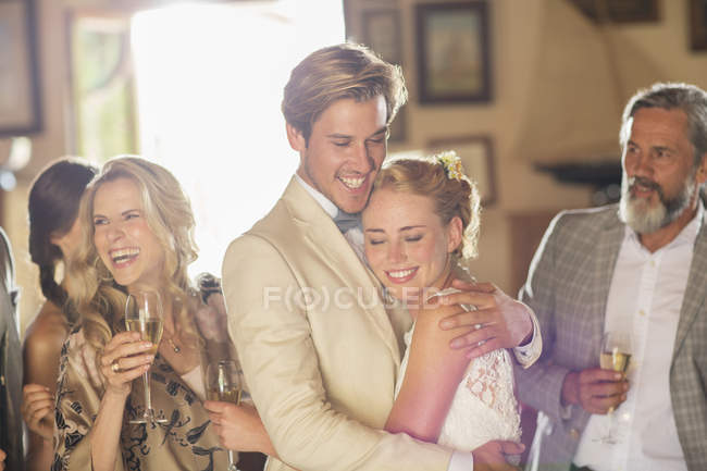 Jeune couple et invités à la réception de mariage dans la chambre domestique — Photo de stock
