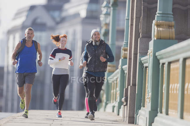 Runners running on sunny urban sidewalk — Stock Photo