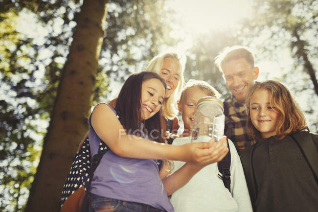 Family holding jar with butterfly in sunny woods — Stock Photo