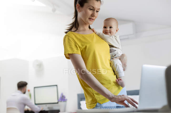 Madre che tiene la figlia del bambino al computer portatile — Foto stock