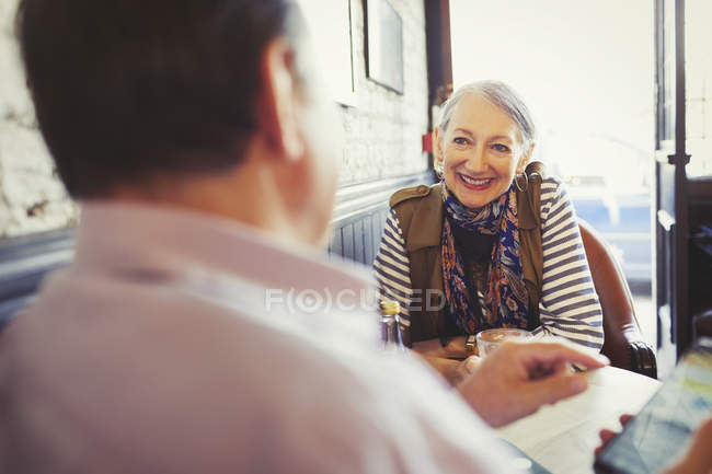 Senior couple talking and using smart phone in cafe — Stock Photo
