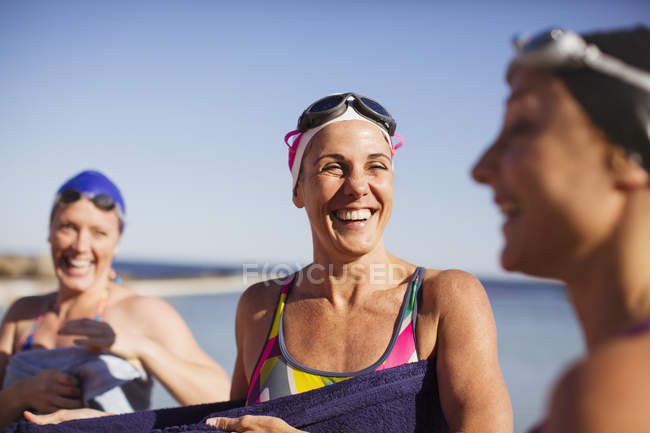 Sorridente Feminino nadadores ativos com toalhas no oceano ao ar livre — Fotografia de Stock