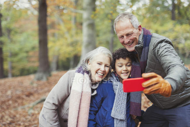 Avós e neto tomando selfie em florestas de outono — Fotografia de Stock
