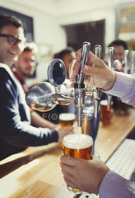 Close up bartender derramando cerveja de torneira alça atrás bar — Fotografia de Stock