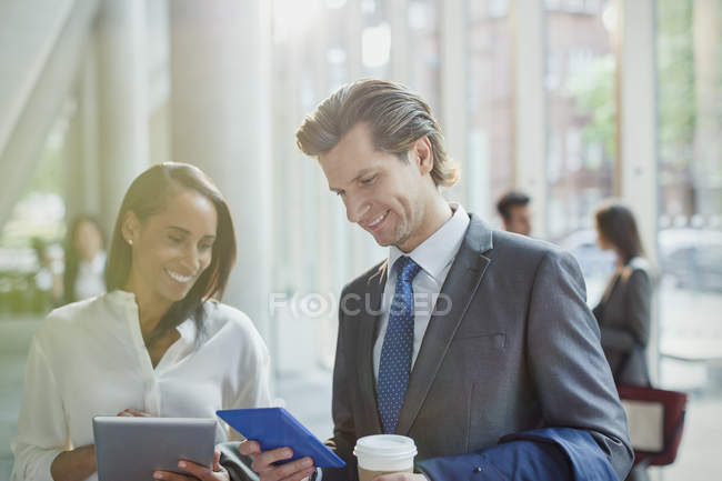 Gente de negocios usando tabletas digitales en el vestíbulo de la oficina - foto de stock