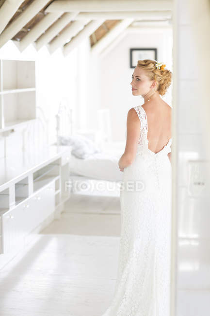 Junge Braut steht im sonnigen Schlafzimmer — Stockfoto