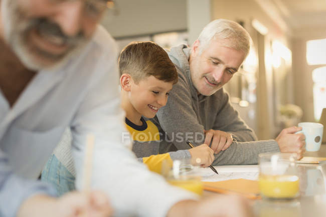 Padre ayudando a su hijo con la tarea en el mostrador - foto de stock