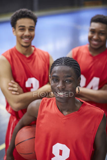 Retrato sonriente, confiado equipo joven jugador de baloncesto masculino en camisetas rojas - foto de stock