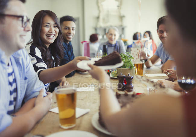 Woman serving chocolate birthday cake to friend at restaurant table — Stock Photo