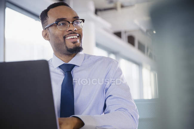 Homme d'affaires souriant travaillant à l'ordinateur portable dans le bureau — Photo de stock