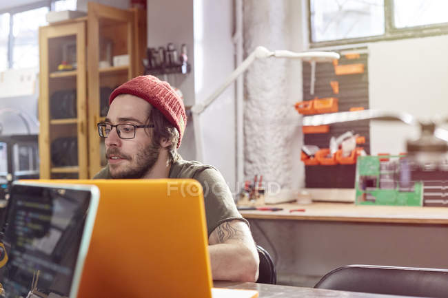 Male designer working at laptop in workshop — Stock Photo