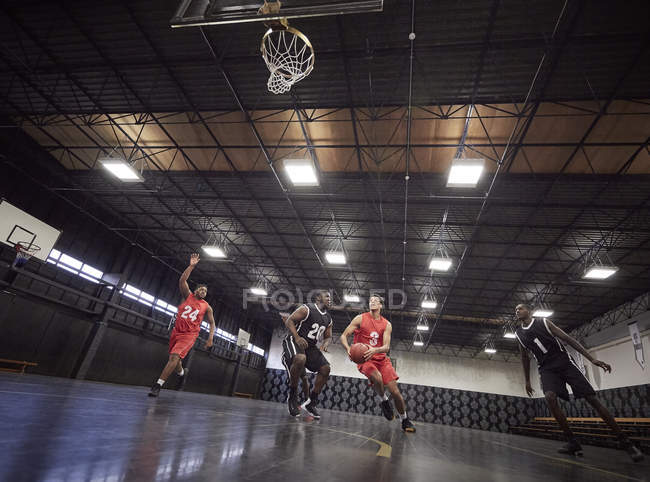 Young male basketball players playing basketball on court in gym — Stock Photo