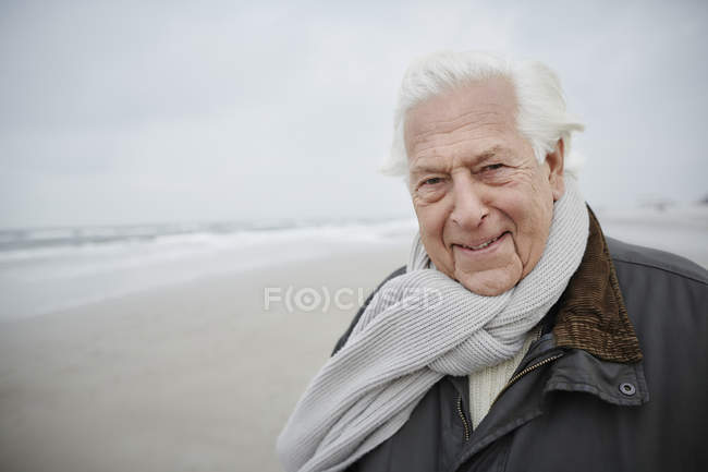 Portrait homme âgé confiant portant une écharpe sur la plage d'hiver — Photo de stock