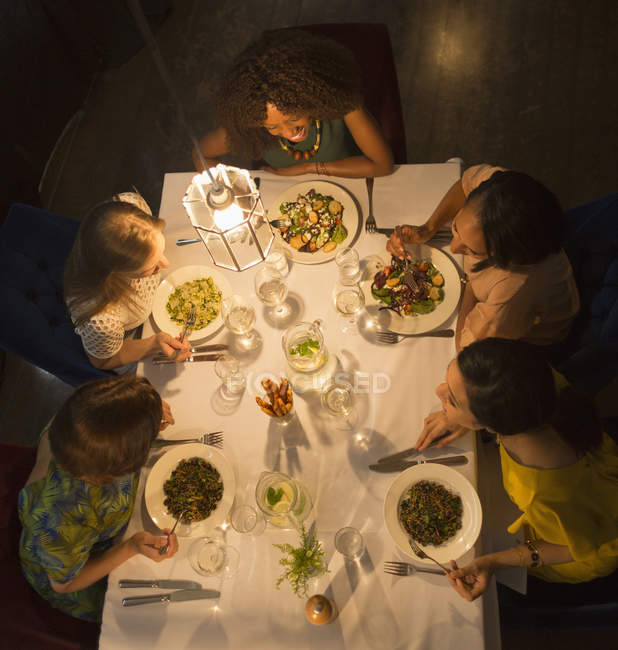 Mujeres amigas hablando y cenando en la mesa del restaurante - foto de stock