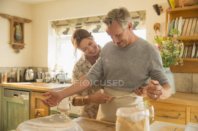 Verspieltes reifes Paar backt Schürze in Küche — Stockfoto