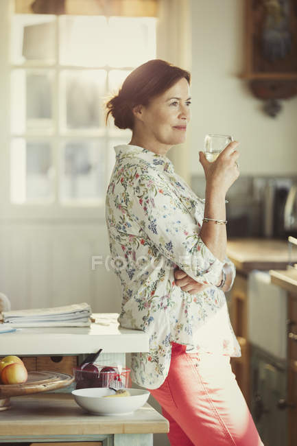 Pensive mature woman drinking wine in kitchen — Stock Photo