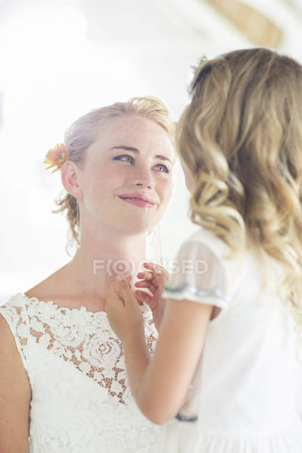 Bride and bridesmaid facing each other and smiling — Stock Photo