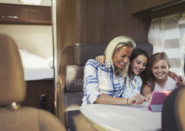 Sorrindo mãe e filhas usando tablet digital dentro de casa do motor — Fotografia de Stock