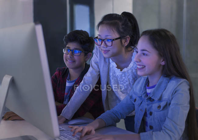 Estudiantes investigando en la computadora en el aula oscura - foto de stock