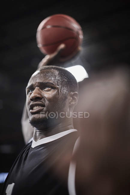 Sérieux, joueur de basket-ball en sueur tenant basket-ball aérien — Photo de stock