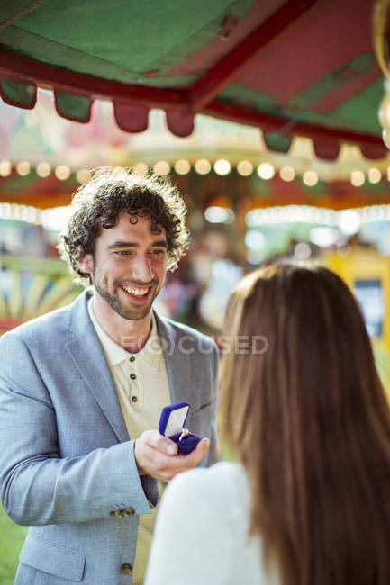 Homem propondo a namorada no parque de diversões — Fotografia de Stock