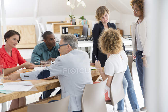 Group of office workers talking at desk — Stock Photo