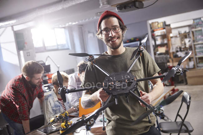 Retrato sorrindo designer masculino segurando drone na oficina — Fotografia de Stock