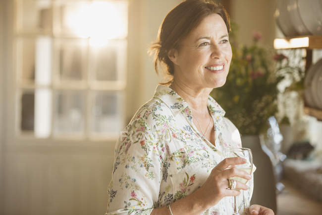 Smiling mature woman drinking wine in kitchen — Stock Photo