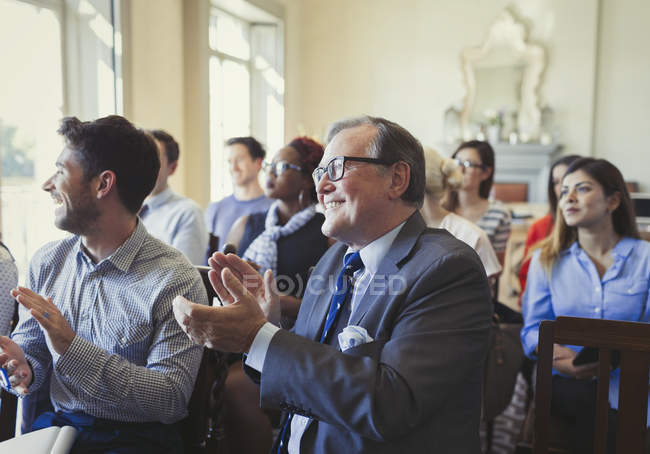 Gente de negocios sonriente aplaudiendo en audiencia de conferencia de negocios - foto de stock