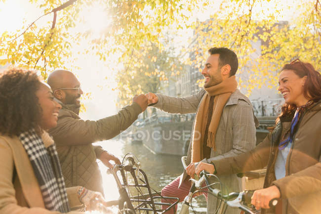 Amigos saludando con puño a lo largo del canal de otoño - foto de stock