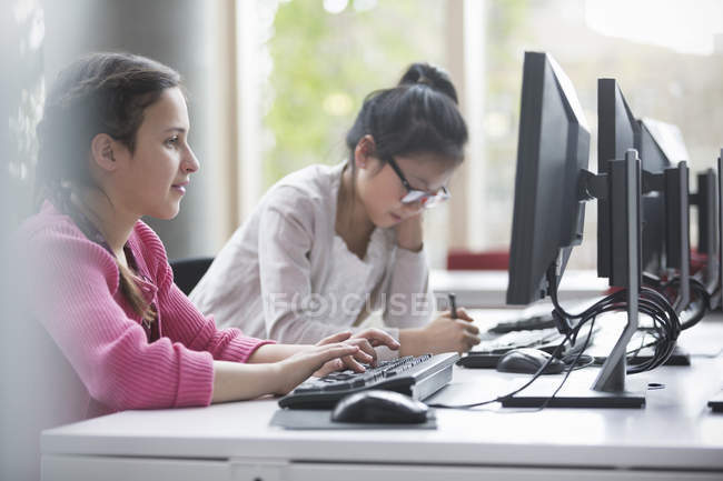 Girl students studying at computers in library — Stock Photo