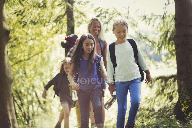Madre e hijas de senderismo en el bosque - foto de stock