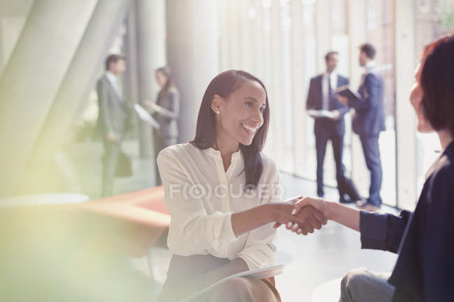 Lächelnde Geschäftsfrauen beim Händeschütteln in der Büro-Lobby — Stockfoto