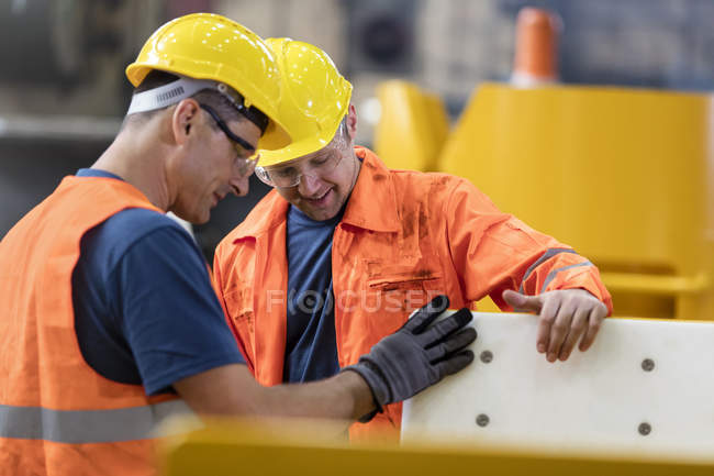Workers examining part in factory together — Stock Photo