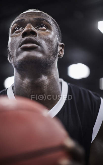 Крупним планом орієнтований молодий чоловік баскетболіст з баскетболом дивиться вгору — стокове фото