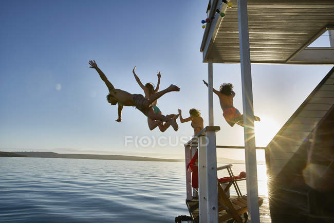 Glückliche junge Freunde springen ins Wasser — Stockfoto