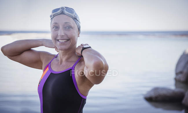 Портрет усміхненої жінки плавець відкритої води, що регулює купальний костюм в океані — стокове фото